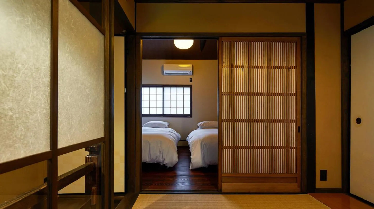une chambre avec deux lits et une porte coulissante à YADORU KYOTO HANARE Kanade No Yado à Kyoto