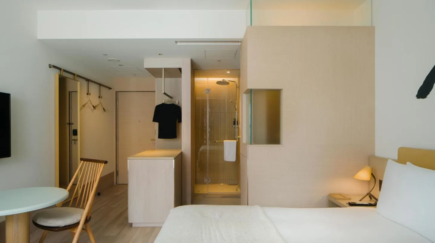 a bedroom with a bed and a table and a kitchen at Zentis Osaka in Osaka