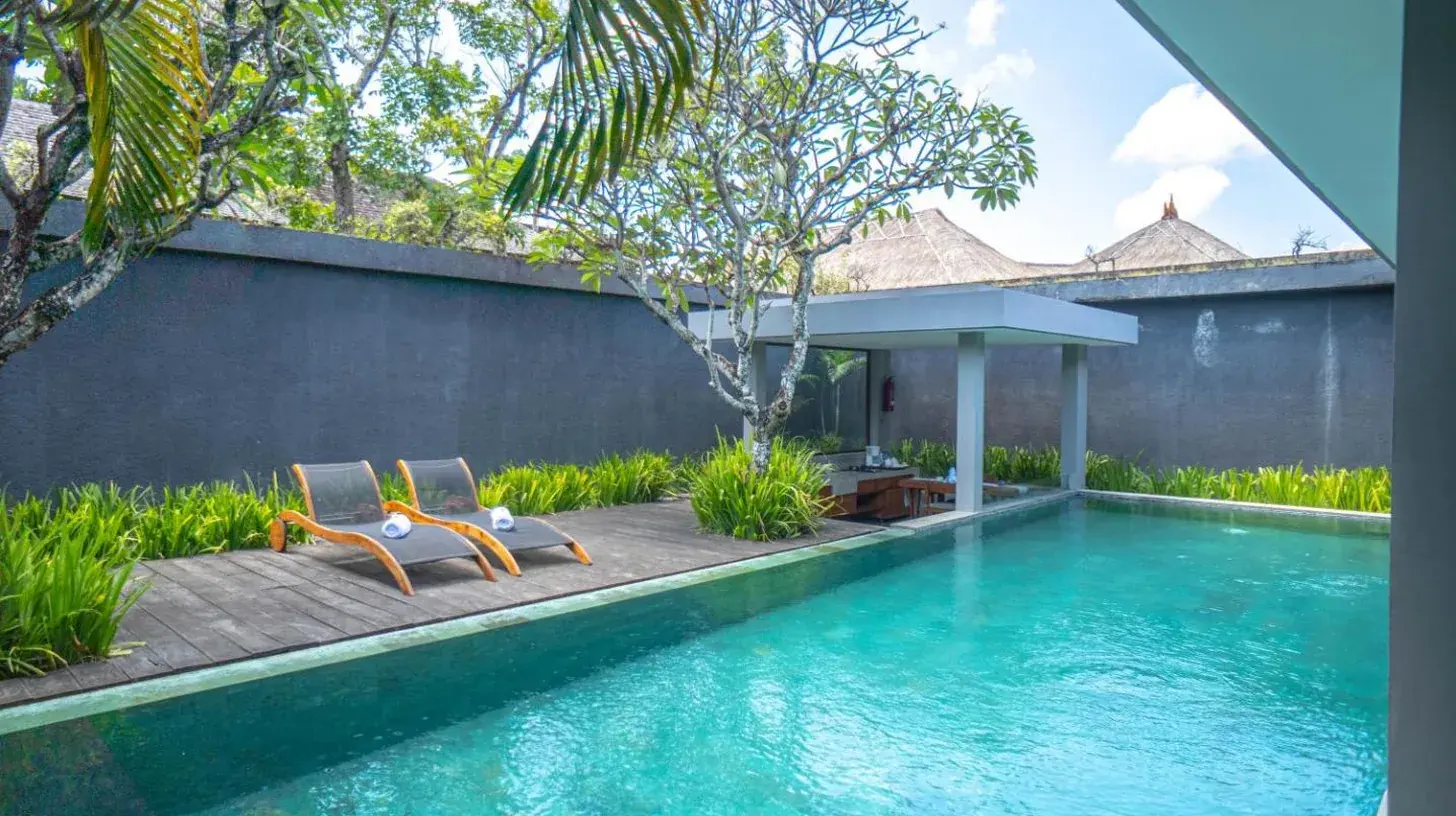 a woman standing next to a large bed in a room at Ziva a Boutique Villa in Seminyak